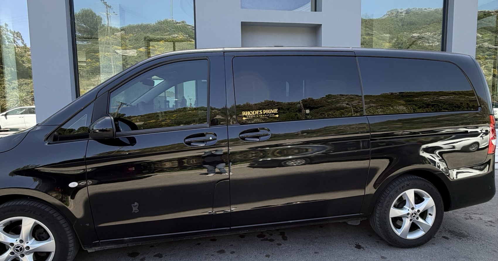 Side view of the black Mercedes van with gold Rhodes Prime lettering on the window
